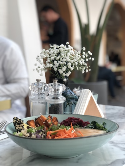 A vibrant bowl of colorful quinoa salad with fresh herbs and lemon wedges on a rustic wooden table.