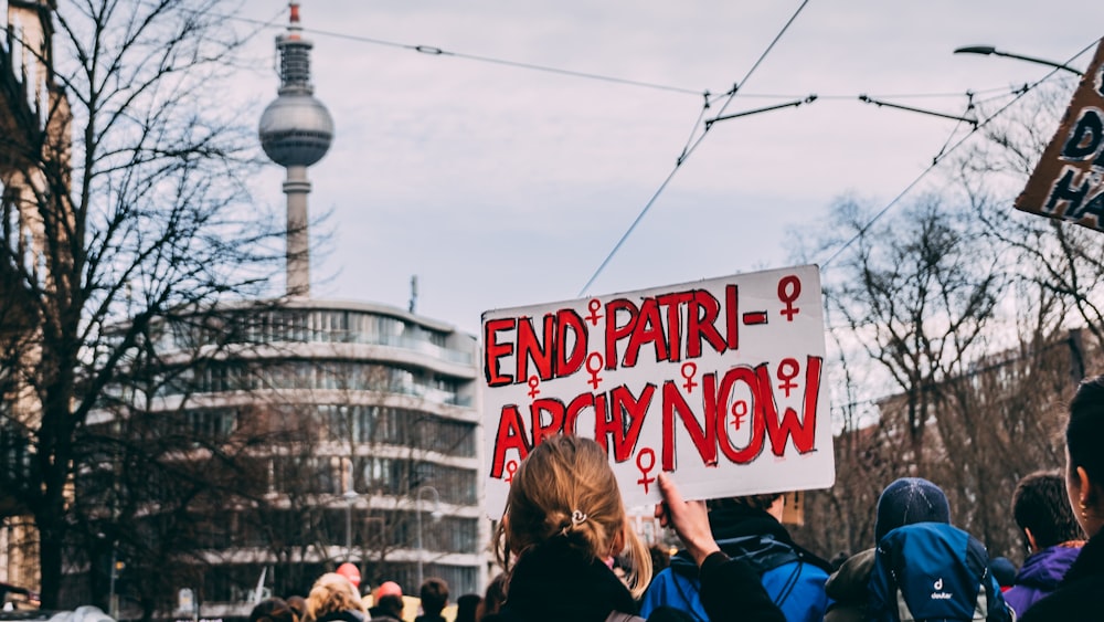 people holding red and white kanji text banner during daytime