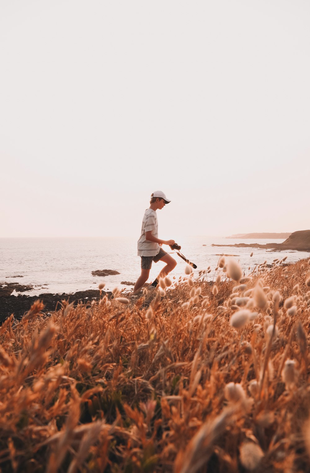 woman in white shirt and blue denim shorts standing on brown grass field near body of on on on on