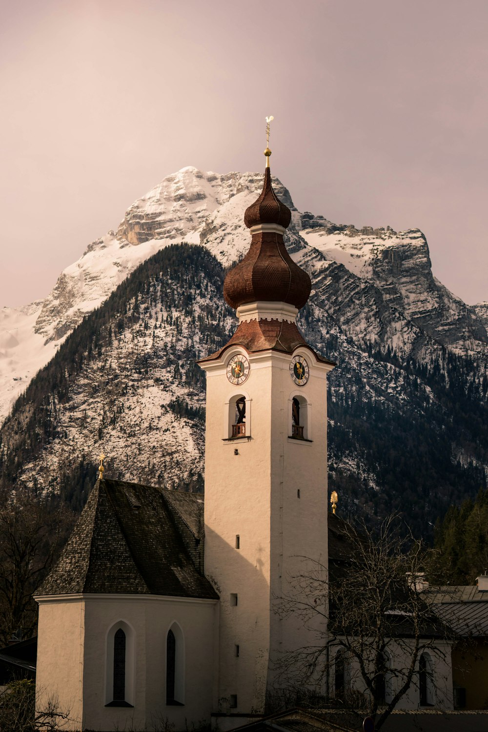 white and brown concrete building near snow covered mountain during daytime