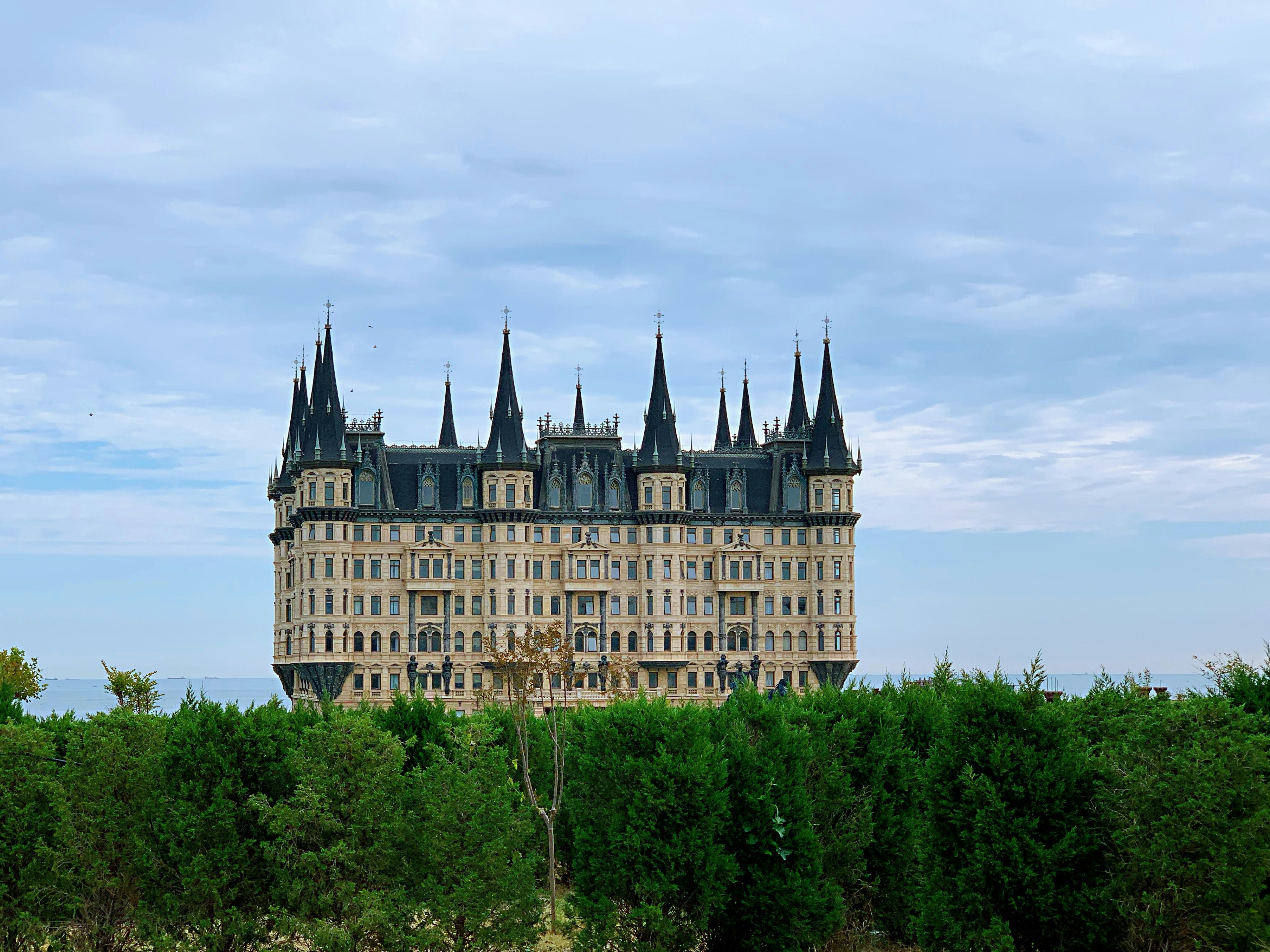 brown and white concrete castle surrounded by green trees under white clouds during daytime, 