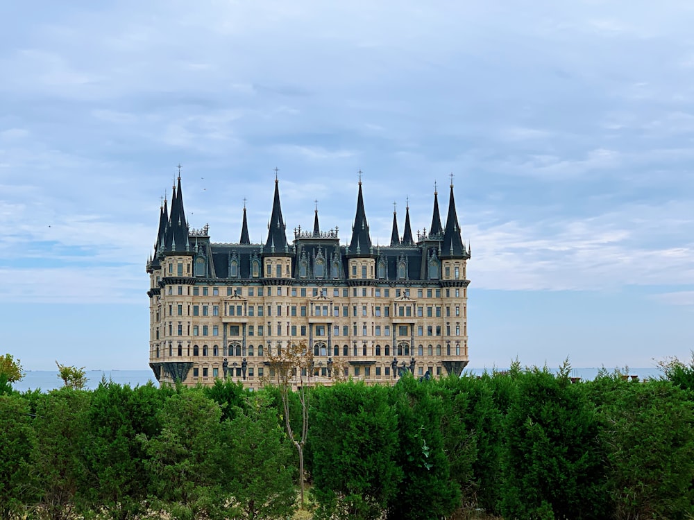 brown and white concrete castle surrounded by green trees under white clouds during daytime