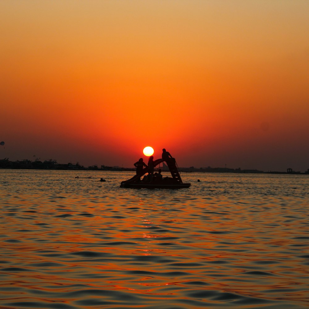 silhouette of man riding on boat during sunset