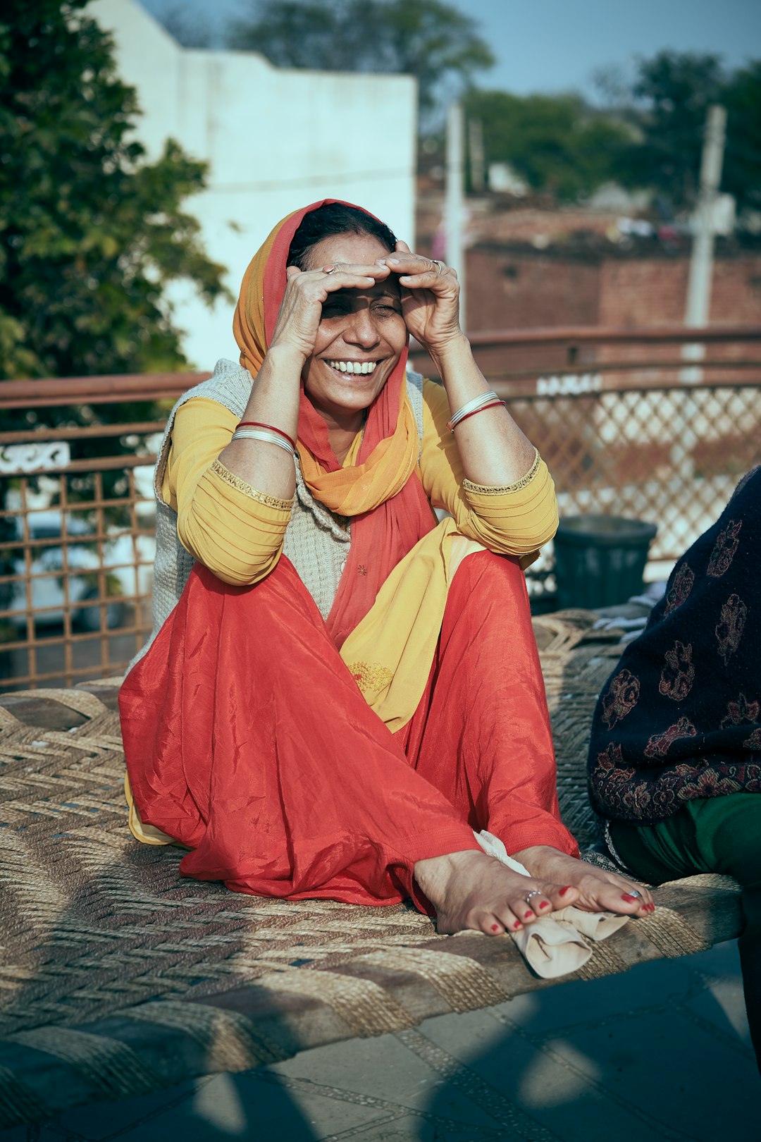 woman in yellow and red sari sitting on brown concrete floor