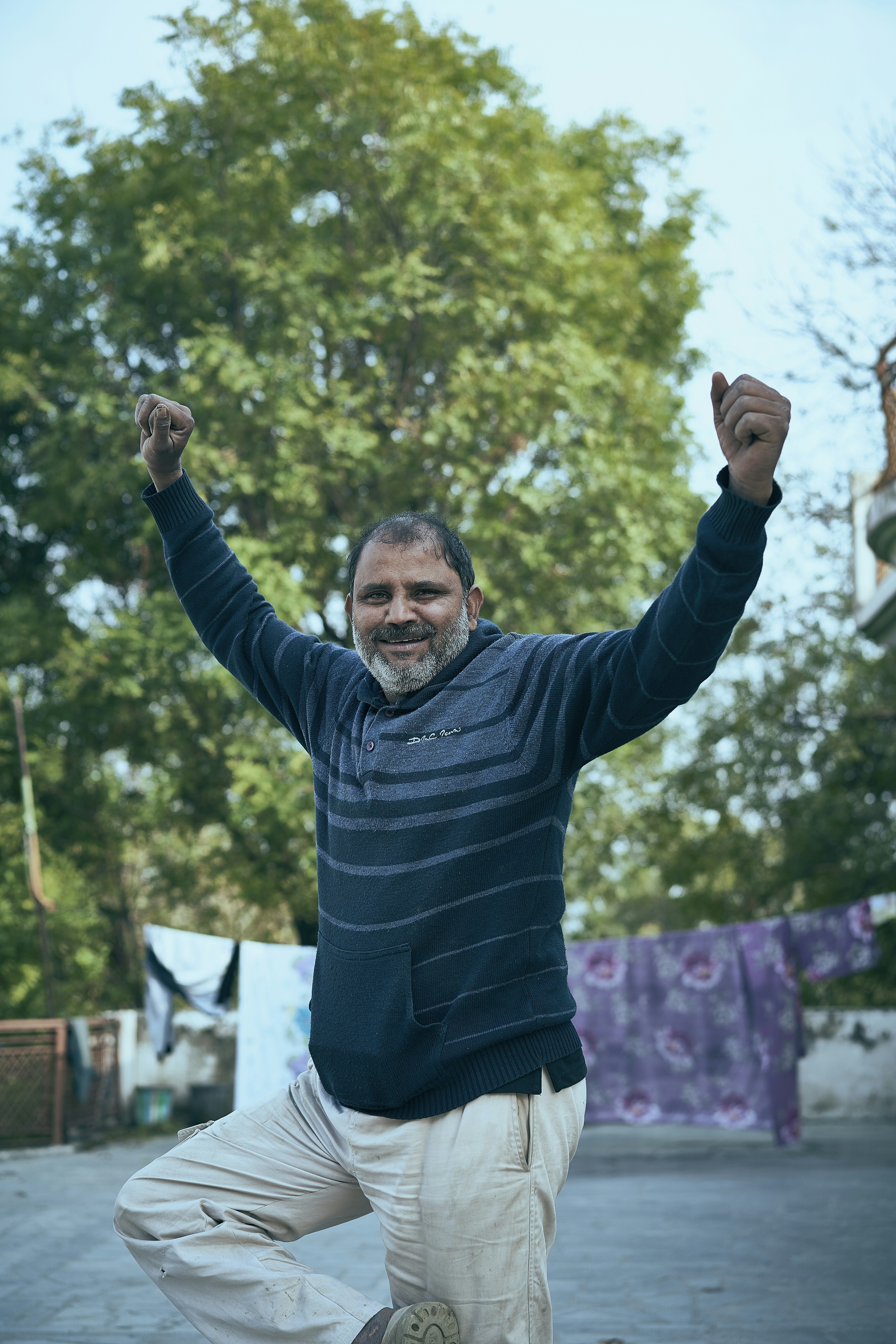 man in blue long sleeve shirt and black pants raising his right hand
