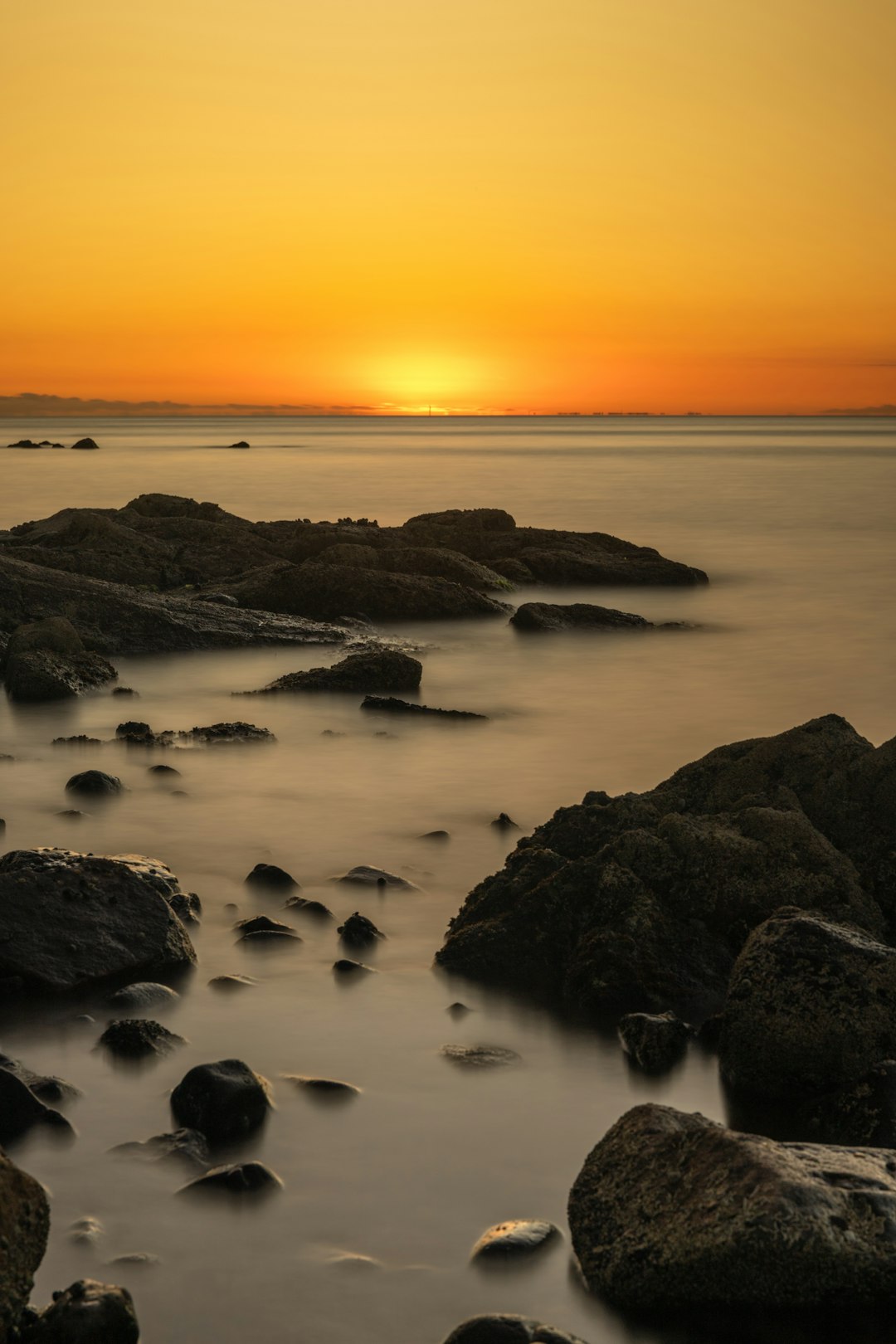 brown rock formation on sea during sunset