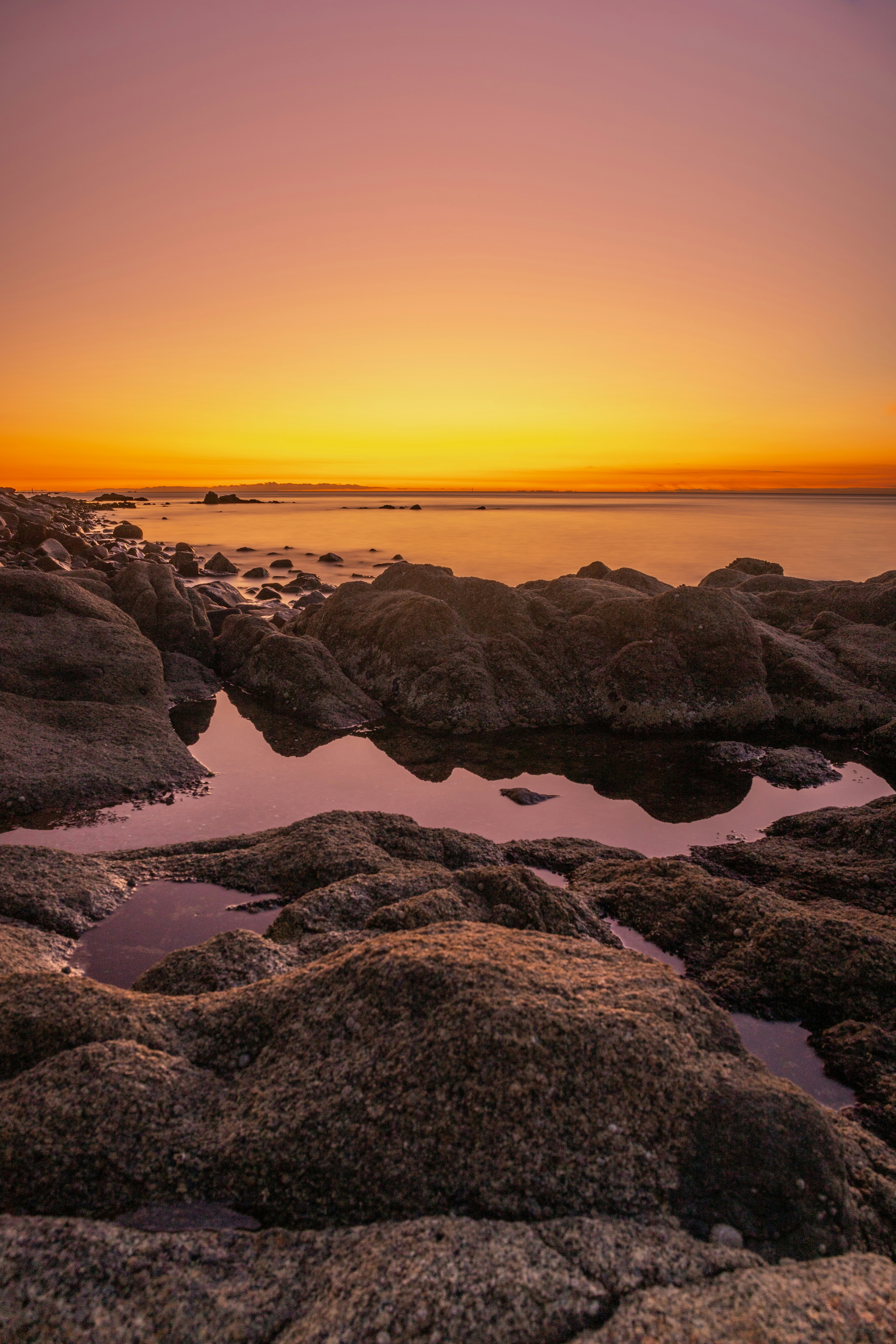 rocky shore during sunset with orange sky
