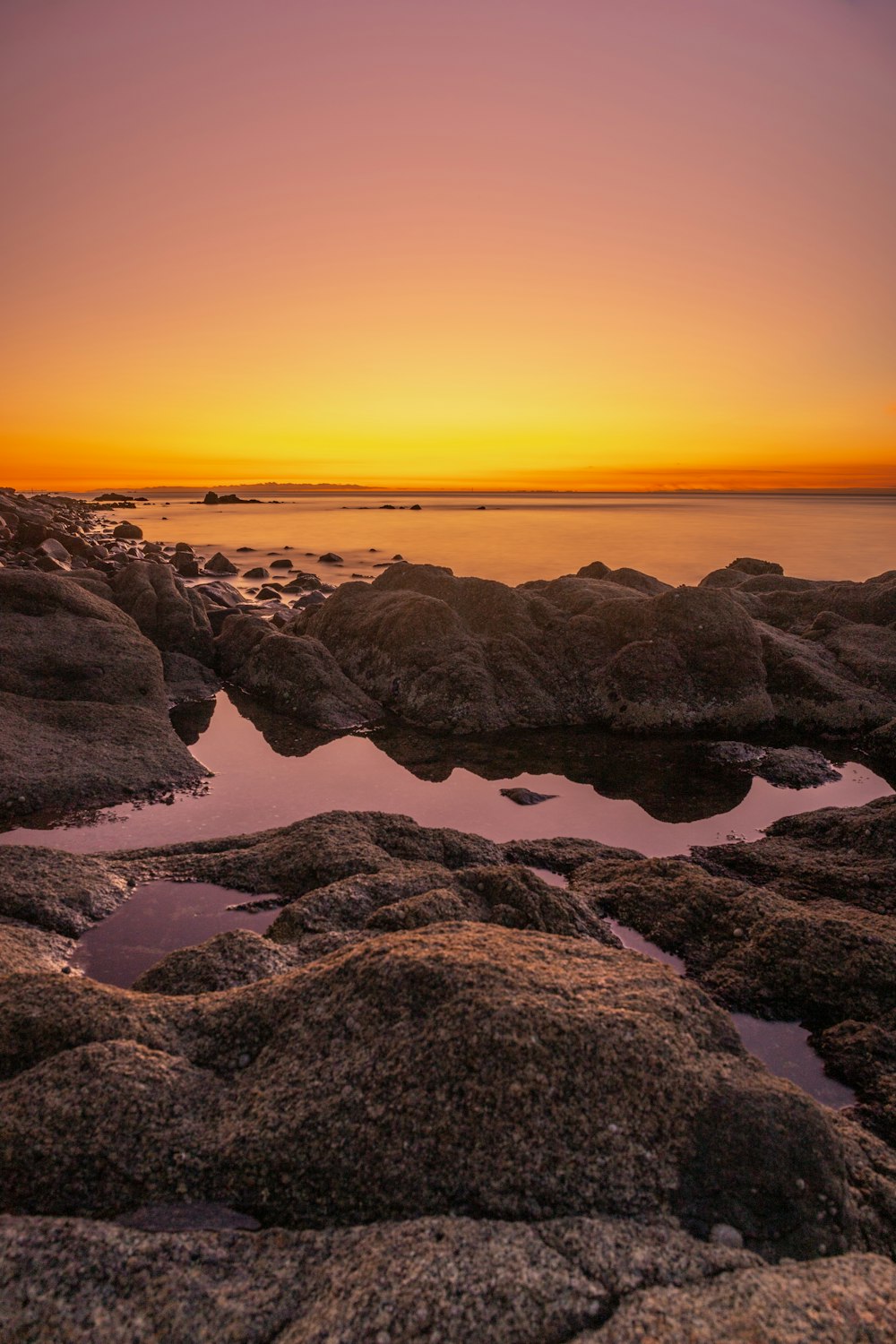 rocky shore during sunset with orange sky