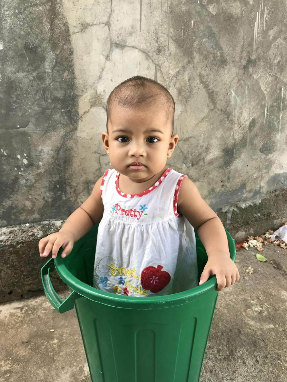 girl in white and pink tank top sitting on blue plastic bucket