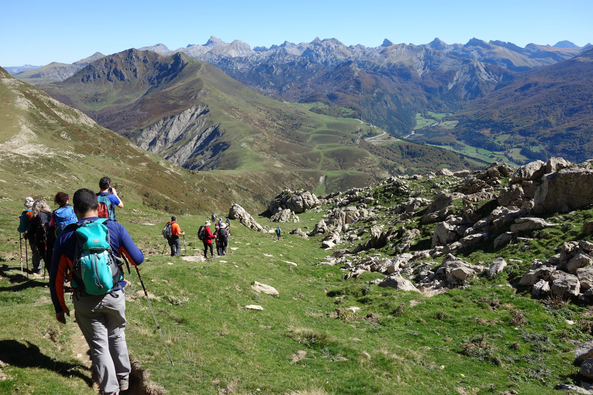 people hiking on green grass field near green mountains during daytime