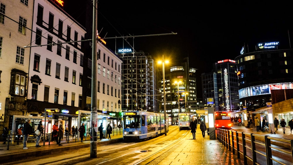 people walking on sidewalk near buildings during night time