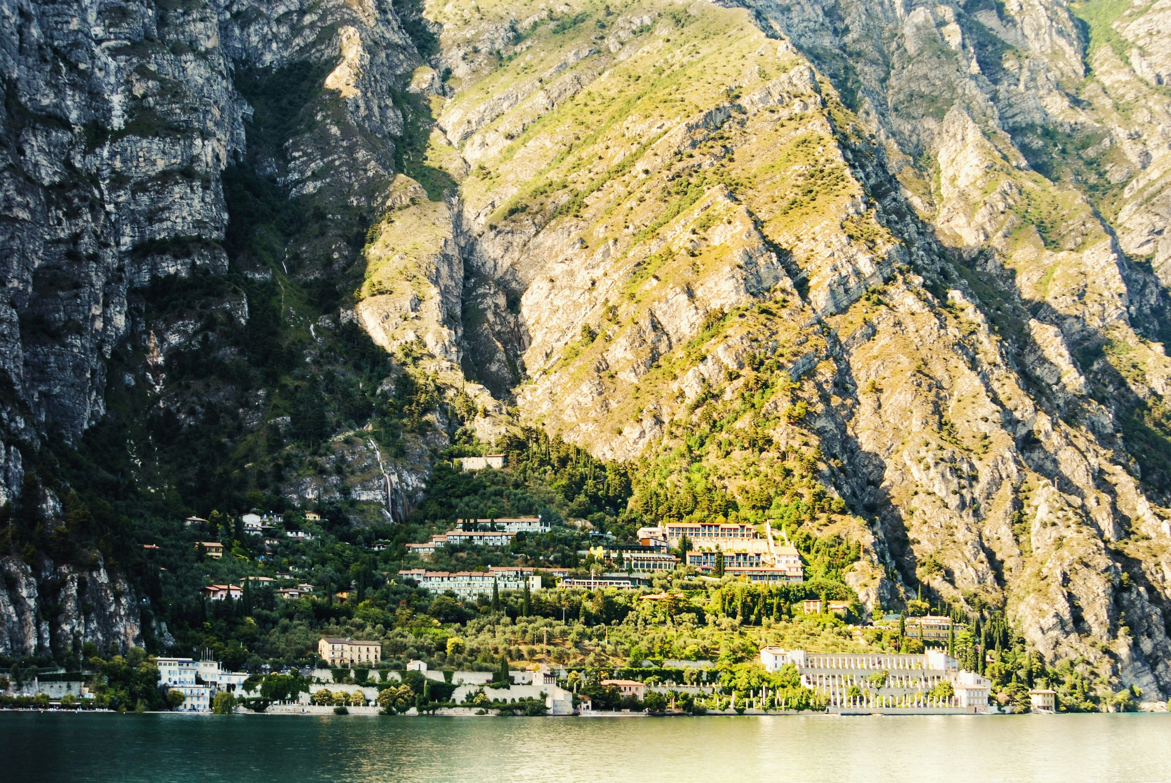 white and brown concrete building near mountain and body of water during daytime