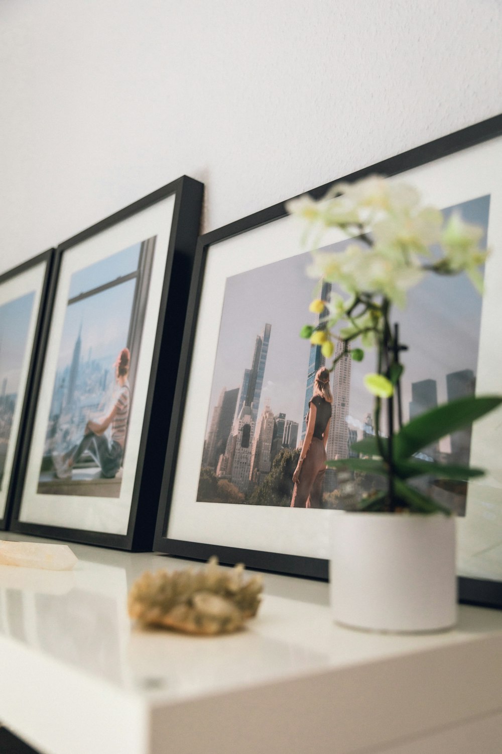 white flowers on white vase beside black wooden framed painting