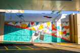 A colorful mural showcasing Islamic geometric patterns intertwined with vibrant Caribbean flora.