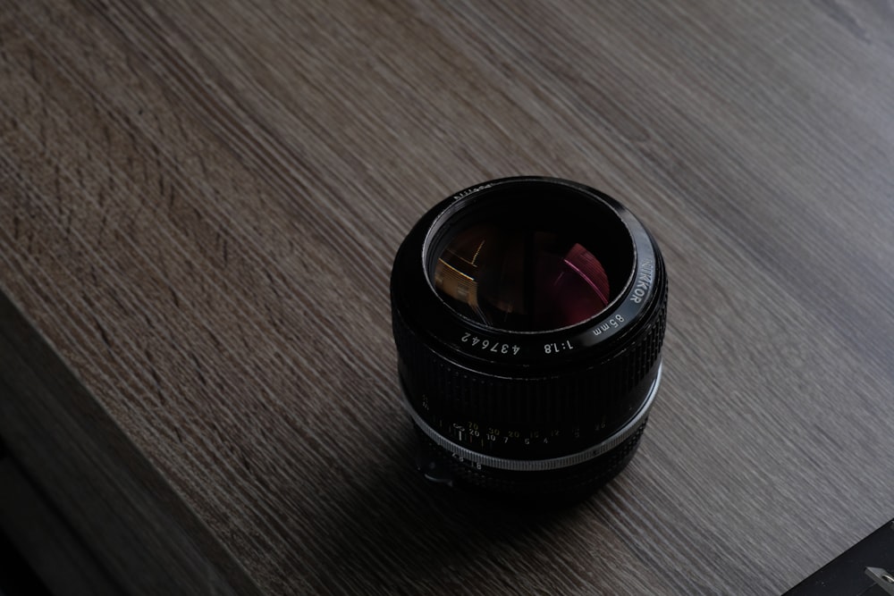 schwarzes Kameraobjektiv auf braunem Holztisch