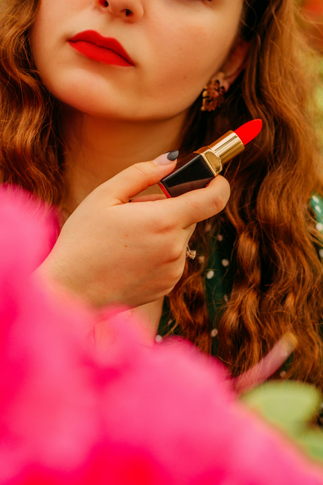 woman in pink shirt holding lipstick