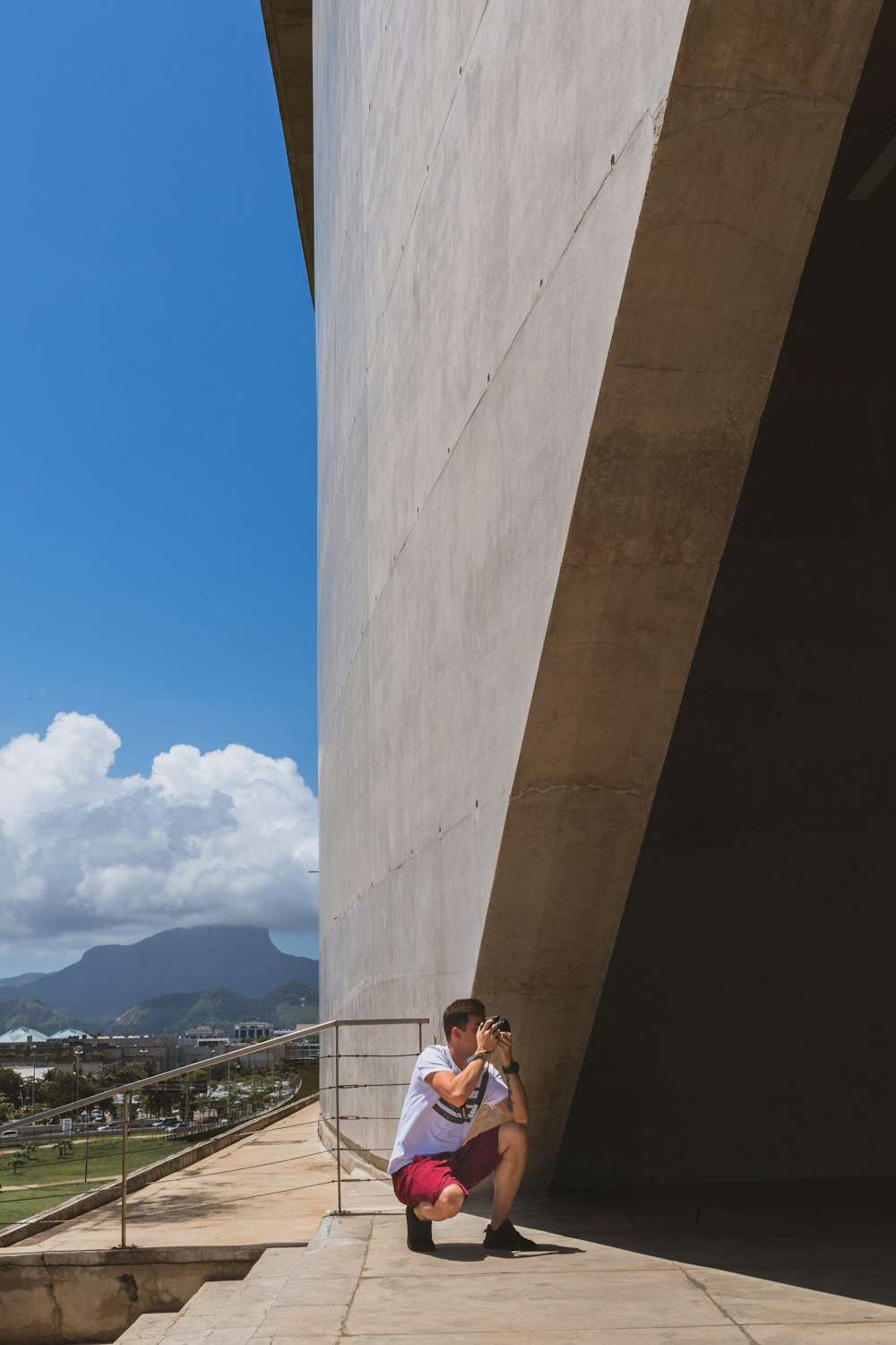 woman in white shirt and black pants standing on brown concrete bridge during daytime