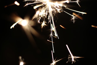 Close-up of glowing sparks showering down with smoky trails illuminating the night air.