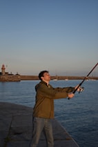 Experienced angler casting a line from a sturdy boat under a clear blue sky.