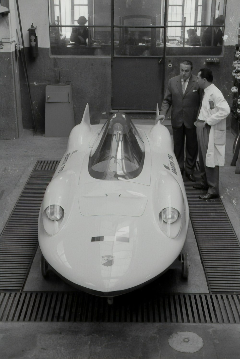 man in black suit standing beside white car