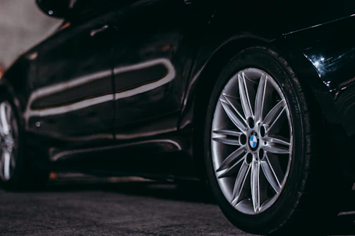Close-up of a sleek BMW alloy wheel adorned with a glossy M Sport sticker shimmering under sunlight.