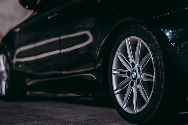 Close-up of a sleek BMW alloy wheel featuring a glossy M Sport sticker under natural sunlight.