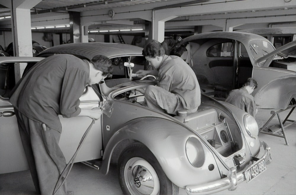 man in gray suit sitting on white vintage car