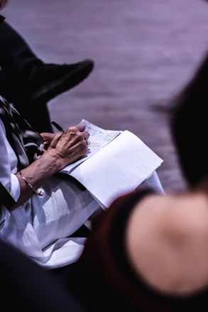 Close-up of hands writing notes during a longevity seminar, with a calming white and green color palette in the background.