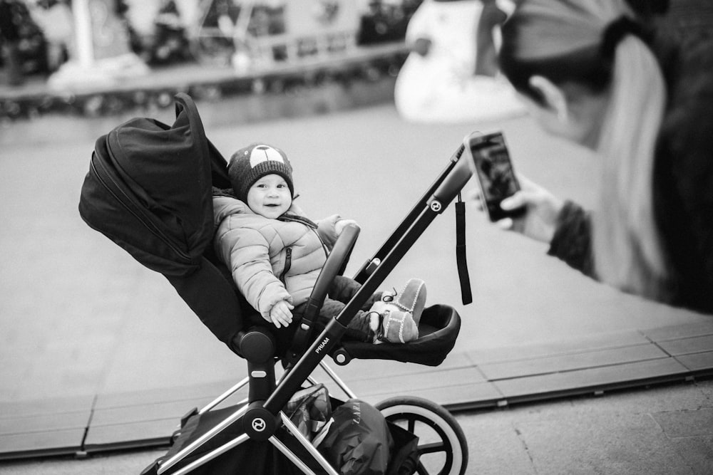 foto em tons de cinza do bebê deitado no carrinho de bebê