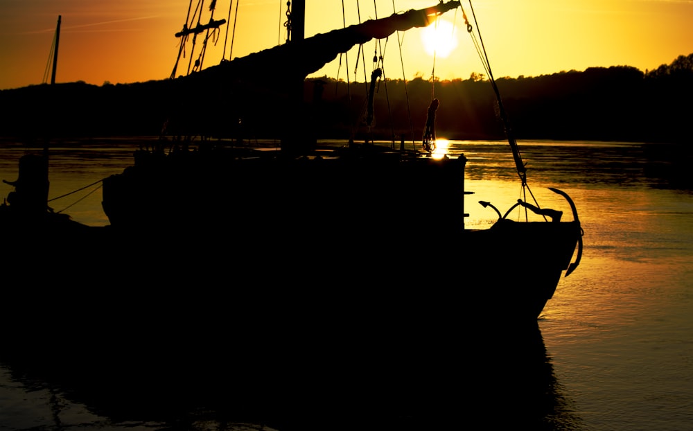 silhouette of boat on sea during sunset