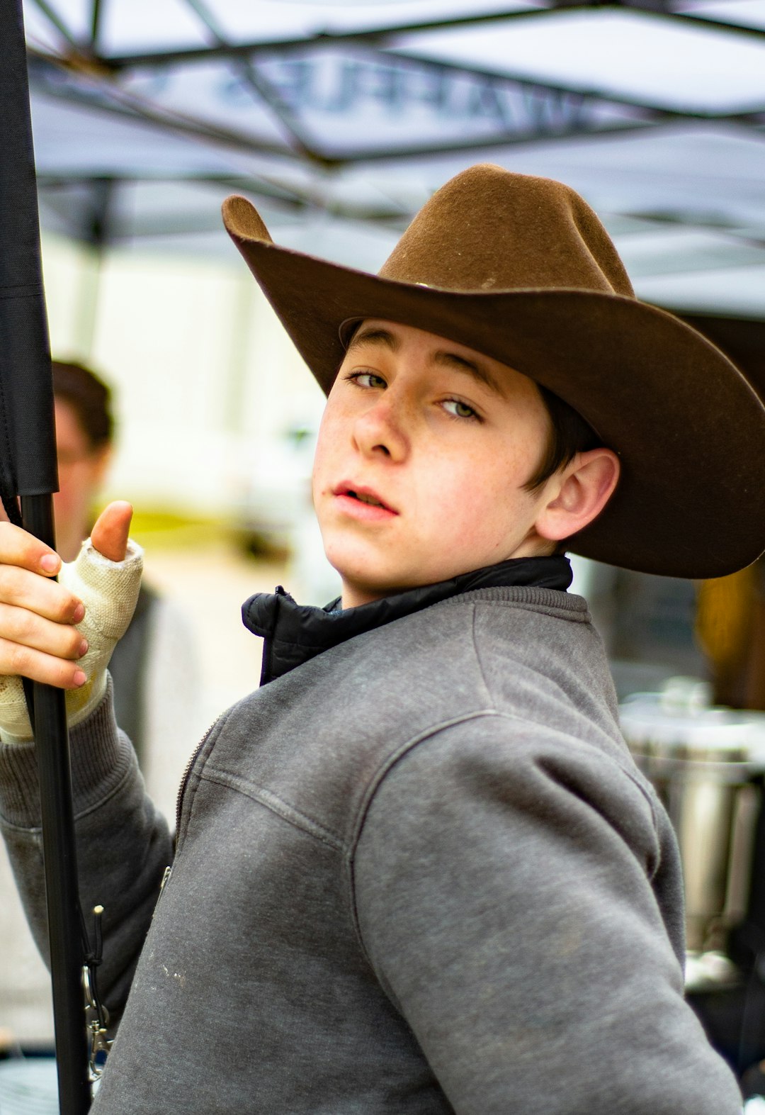 boy in black cowboy hat holding black metal rod