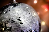 A close-up view of a monochrome globe highlighting regions of Eastern Europe and Central Asia, including countries like Kazakhstan, Uzbekistan, and Iran. The globe is positioned at an angle, with names of cities and geographical details clearly visible. Soft, blurred lights are seen in the background, creating a warm atmosphere.