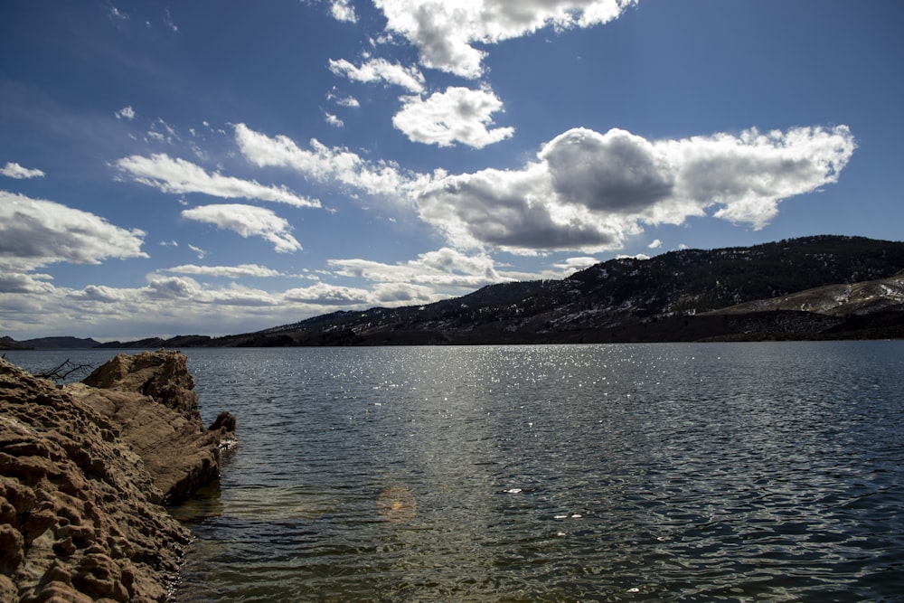 body of water near mountain under blue sky during daytime