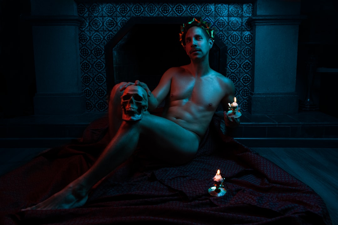 topless man sitting on floor with lighted candles