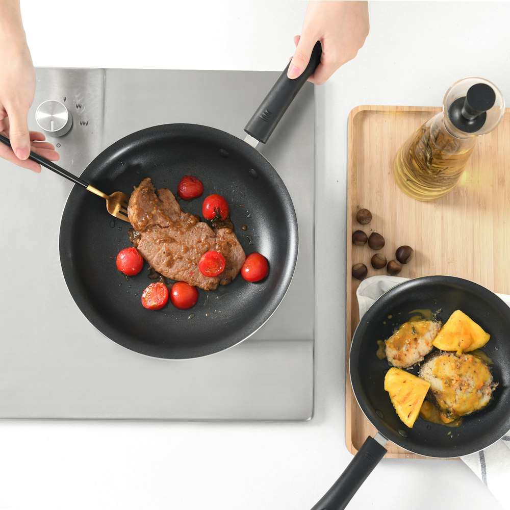 Person mit schwarzer Pfanne mit frittiertem Essen