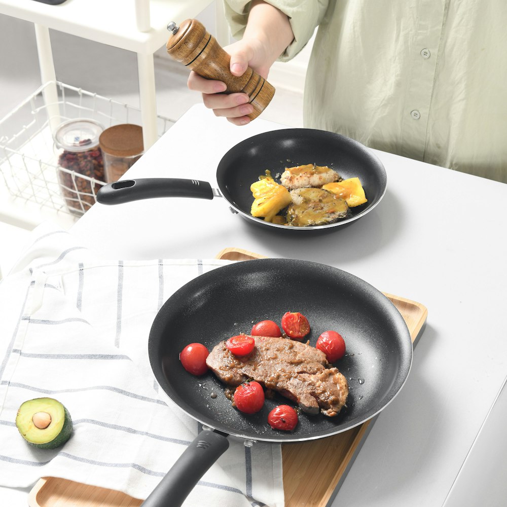 person holding black frying pan with fried food
