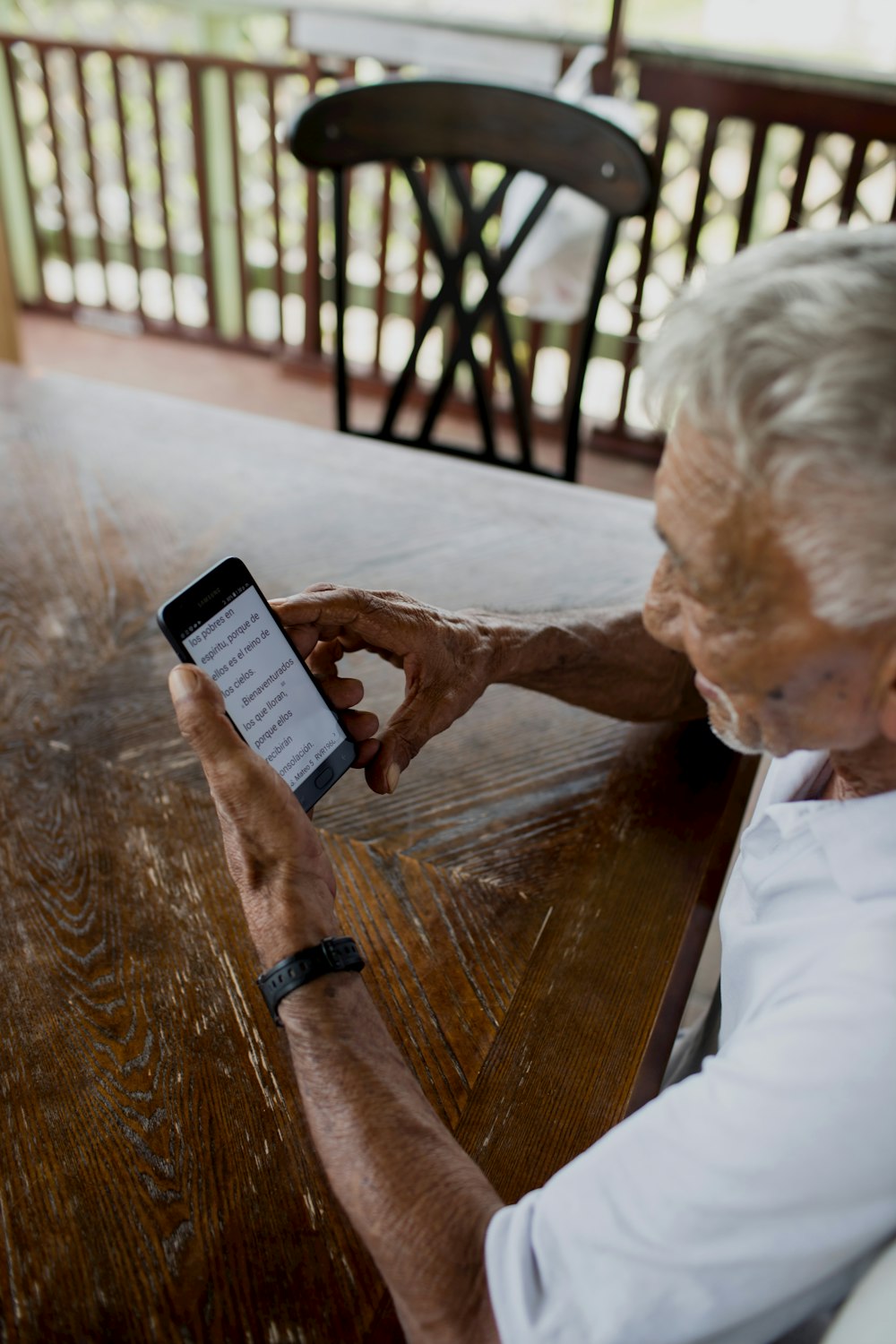 person holding black smartphone on brown wooden table