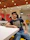 Close-up of a man proudly showing off his colorful custom t-shirt in a cozy cafe setting.