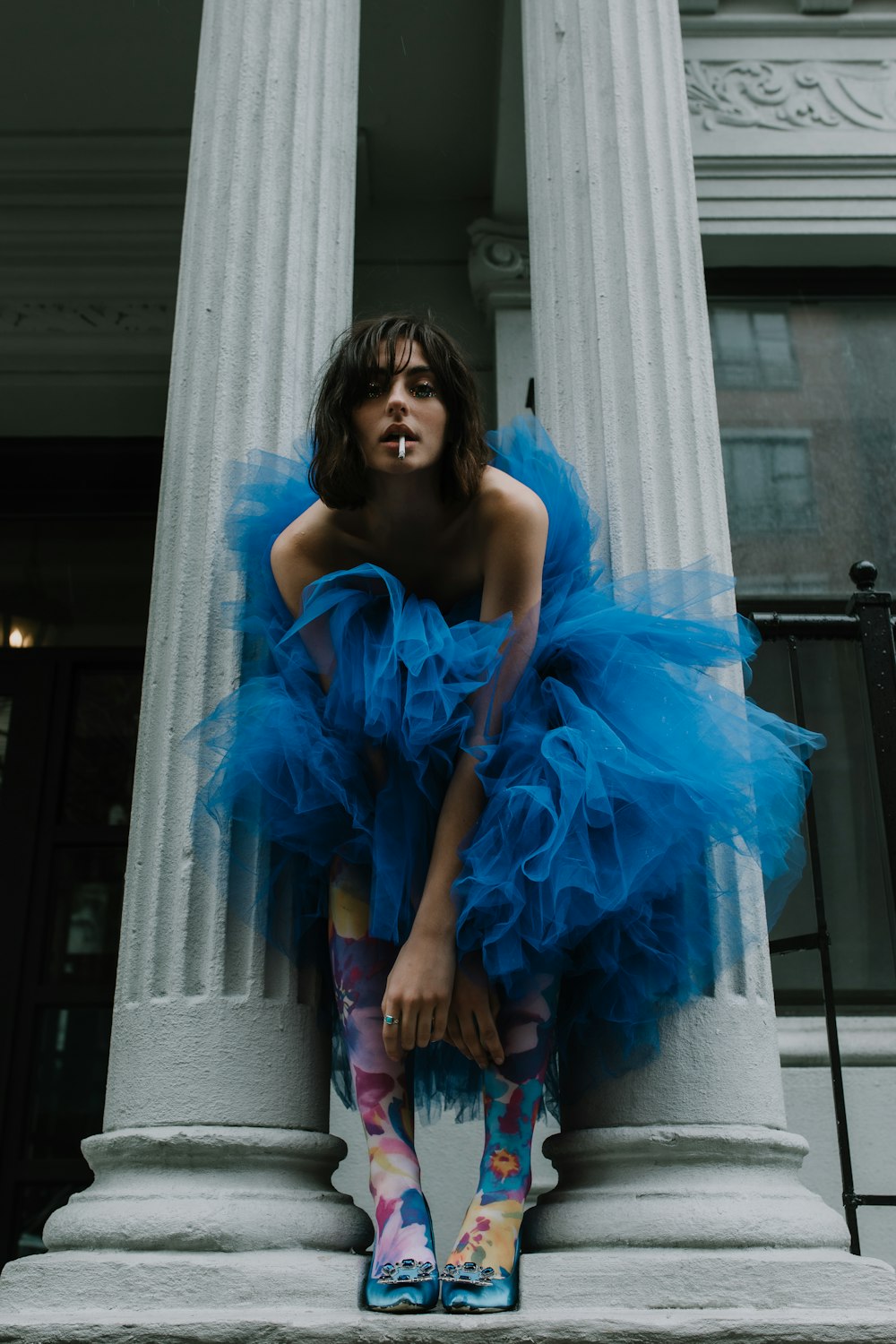 femme en robe tube bleu debout à côté d’un rideau blanc