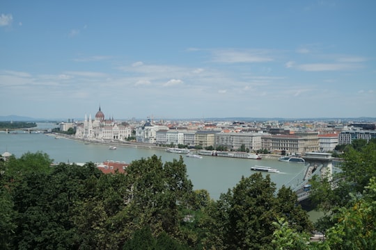 white and blue buildings near body of water under blue sky during daytime in Hungarian Parliament Building Hungary