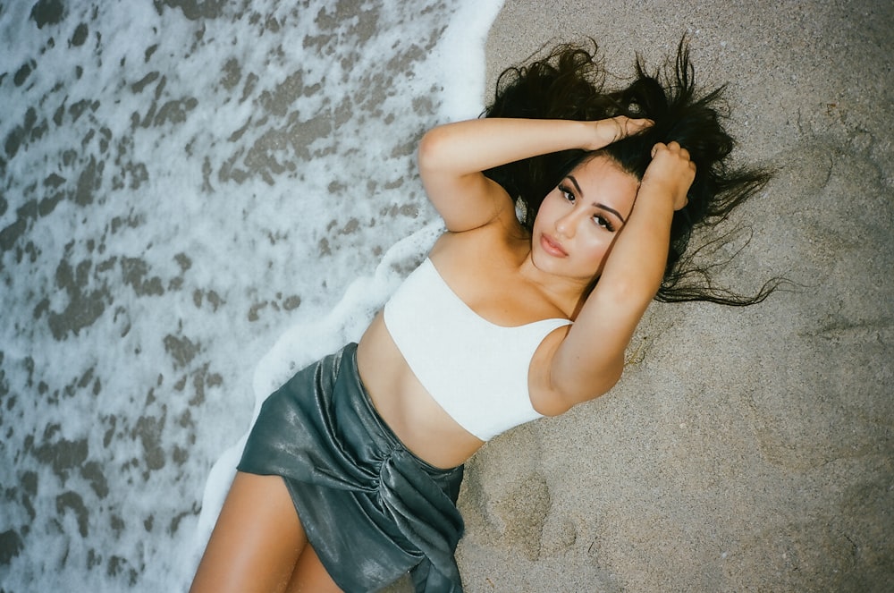 woman in white tank top lying on sand