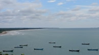 A serene coastal view with fishing boats at sunrise.