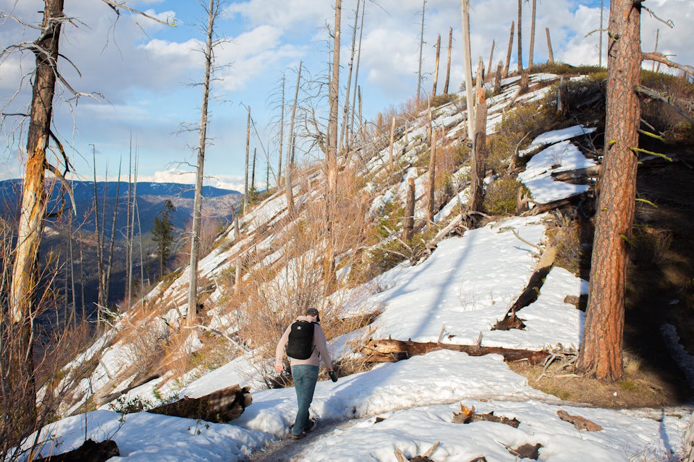 person in black jacket and gray pants standing on snow covered ground during daytime