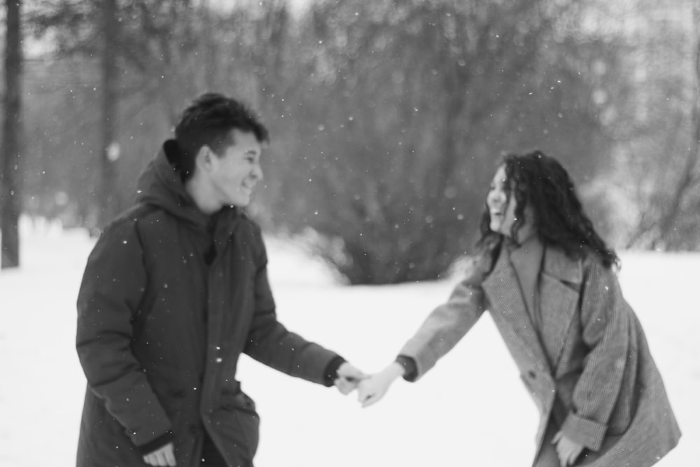 man and woman in winter coat walking on snow covered ground during daytime