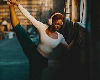 a woman in a white shirt and headphones doing a dance pose
