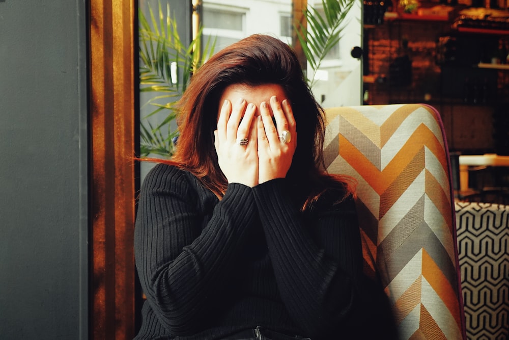 woman in black long sleeve shirt covering her face 