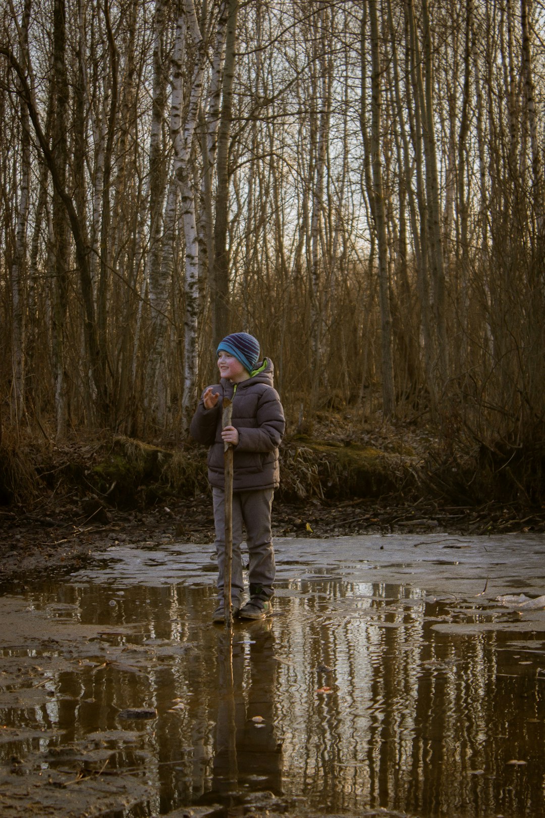 man in brown jacket and gray pants standing on river during daytime