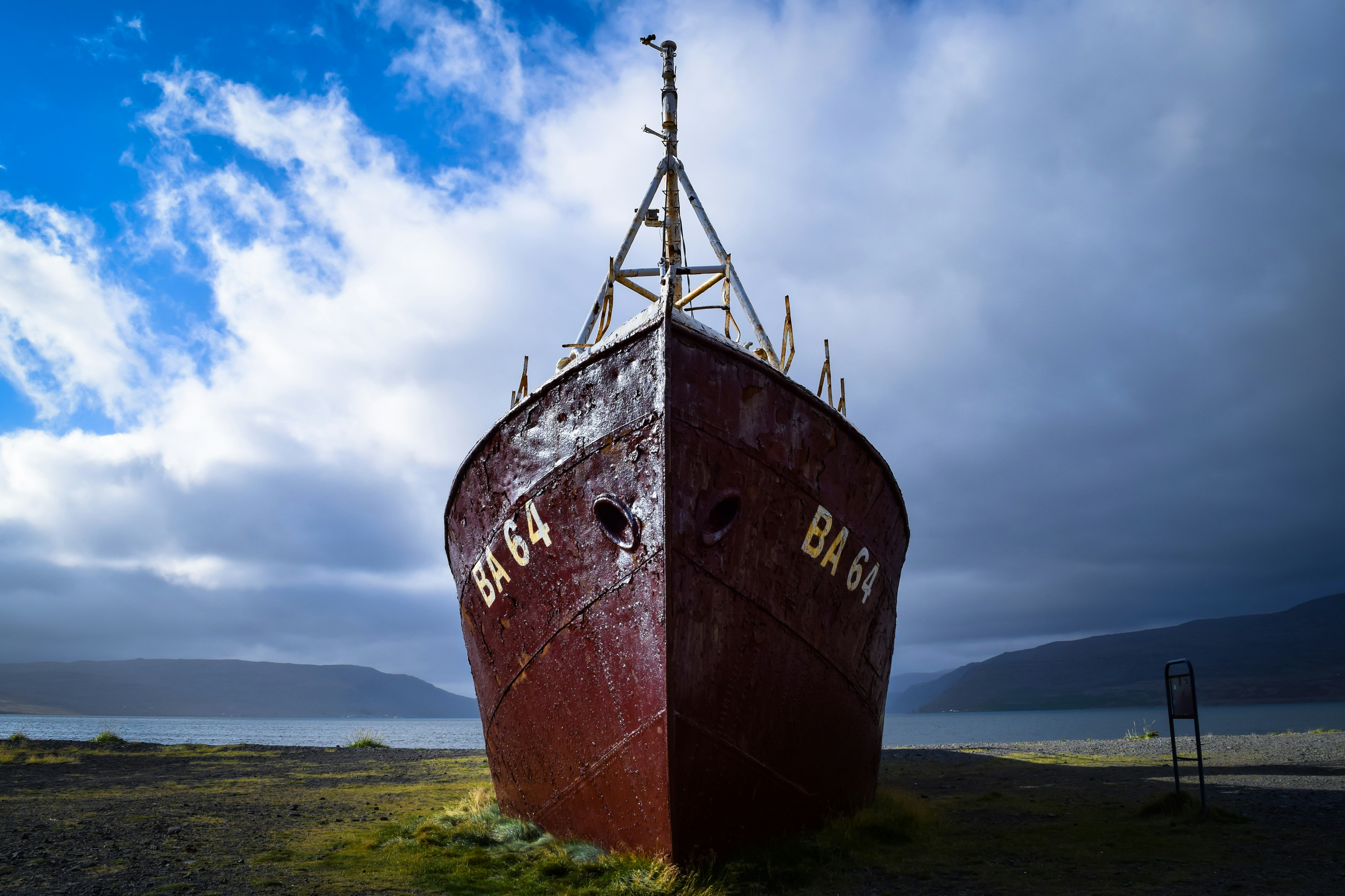 brown ship on green grass field under cloudy sky during daytime