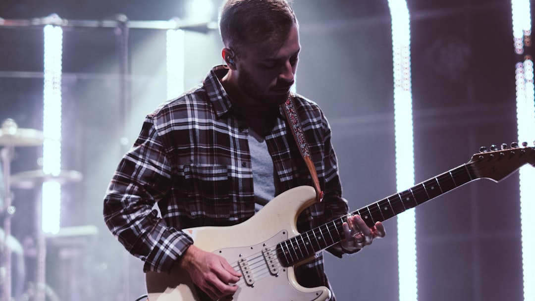 man in black white and blue plaid dress shirt playing electric guitar