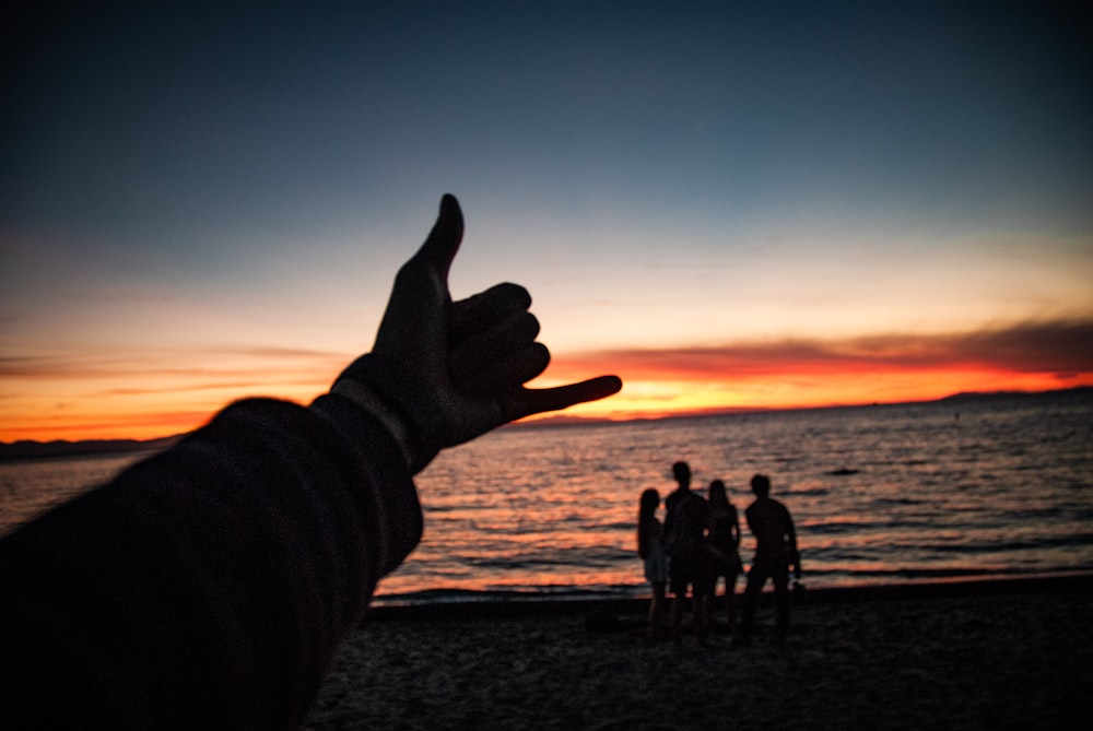 Silueta de la gente en la playa durante la puesta del sol